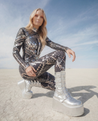 Woman in black sequin and rhinestone jumpsuit with silver platform boots.